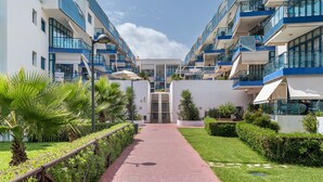 Un hôtel moderne doté d’une allée centrale, de balcons et de verdure.