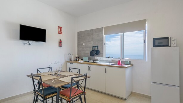Une cuisine moderne avec un coin repas, un téléviseur à écran plat, un four à micro-ondes et une vue sur la mer.