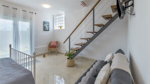 Un intérieur moderne avec un escalier, un canapé, un fauteuil et une plante en pot.