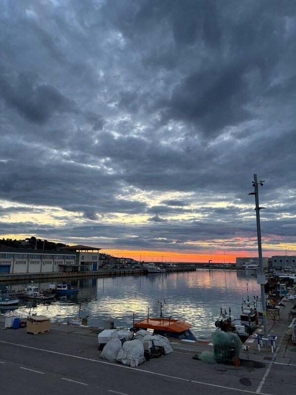 A marina with boats docked, a calm water body, and a cloudy sky.