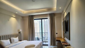 Habitación de hotel moderna con una cama grande, un escritorio, una silla y un televisor en la pared.
