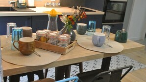 A kitchen with a wooden table, blue chairs, and various kitchen items.