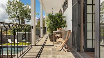 Un balcon avec une piscine, des chaises et une table sur laquelle se trouve un saladier rempli de fruits.