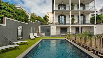 Un bâtiment moderne à deux étages doté d’une piscine, d’un espace extérieur aménagé et d’un balcon.
