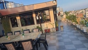 Eine Dachterrasse mit Schachbrettmuster-Boden, Topfpflanzen und einem Tisch mit Stühlen.