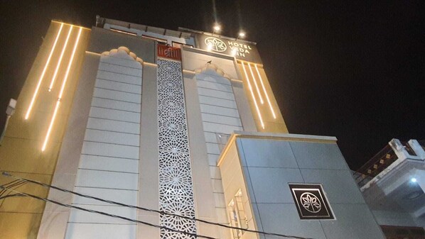 A hotel entrance with a prominent vertical structure, a signboard with the hotel's name, and a logo on the building.
