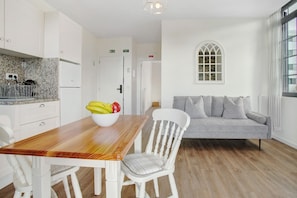 A modern kitchen with white cabinets, a wooden table, and a bowl of fruit. - Studio Apartment '4' with Sea View, Shared Pool and Wi-Fi (Funchal)