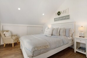 A bedroom with a bed, a chair, a nightstand, and a wall sign. - Studio Apartment '6' with Sea View, Shared Pool and Wi-Fi Access (Funchal)