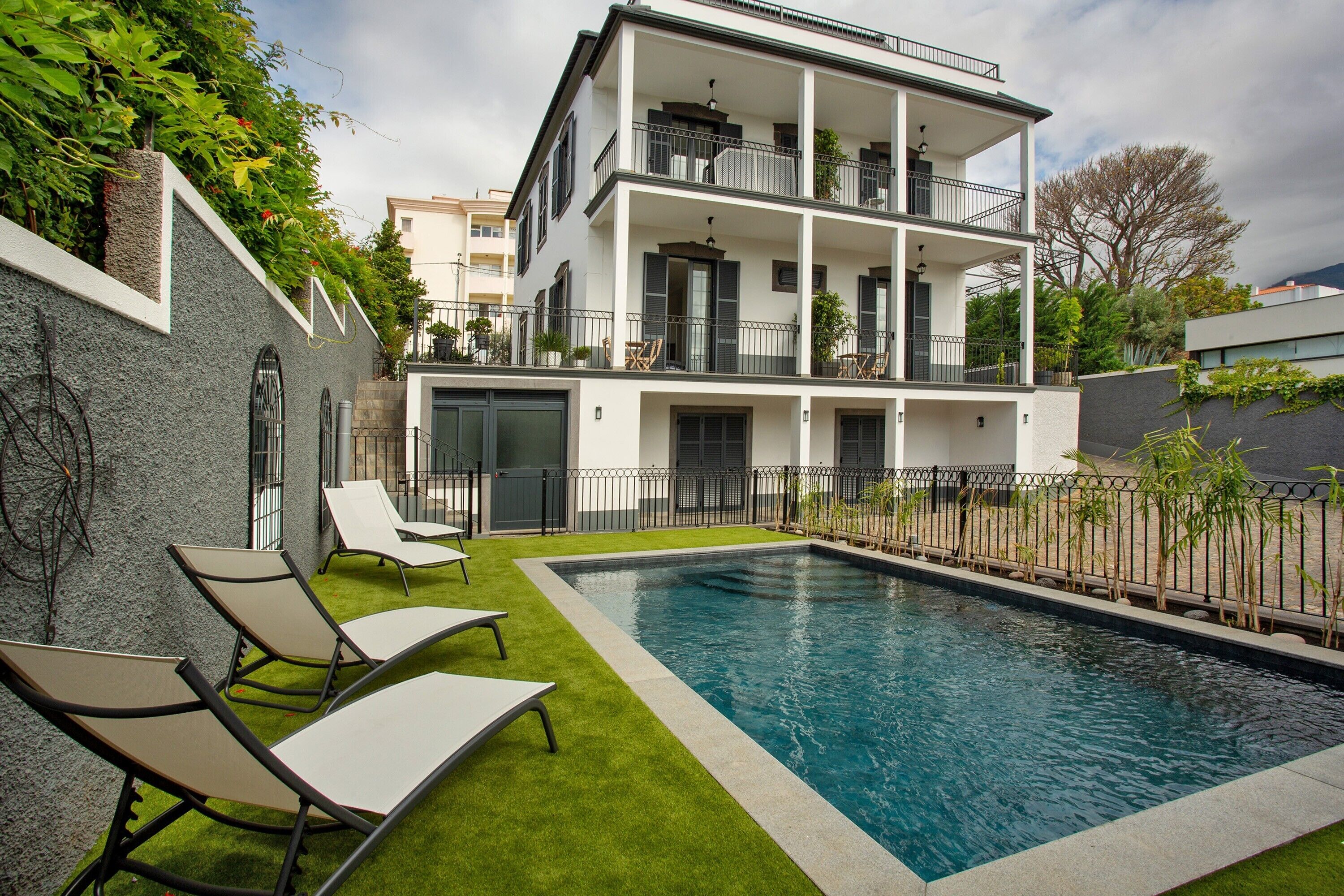 A two-story building with a swimming pool, outdoor seating, and a balcony.