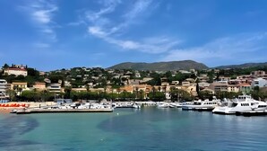 A coastal marina with boats, a clear sky, and buildings on a hillside. - Studio Apartment 'Chez Lina -  Avec Terrasse' with Private Terrace and Wi-Fi (Le Lavandou)