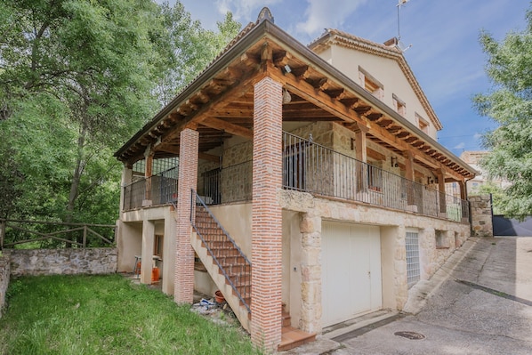 A two-story building with a balcony, stone walls, and a staircase leading to the upper floor.