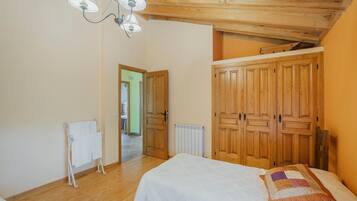 A bedroom with a wooden ceiling, a bed with a quilt, a radiator, and a wardrobe.
