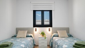 A bedroom with two beds, a nightstand, a window, and a plant. - Holiday Home 'El Rincón Del Sur 2' with Private Pool, Wi-Fi and Air Conditioning (Barrio Nuevo)