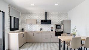 A modern kitchen with white tiled backsplash, built-in appliances, and a dining area with a table and chairs. - Holiday Home 'El Rincón Del Sur 2' with Private Pool, Wi-Fi and Air Conditioning (Barrio Nuevo)