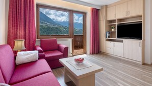 A living room with a sofa, a coffee table, a TV, and a window with a mountain view. - Apartment 'Christine 1' with Mountain View, Shared Pool and Wi-Fi (Riffian)