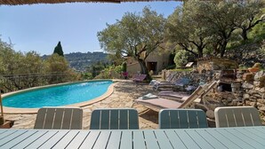 A poolside area with lounge chairs, a table, and a stone wall.