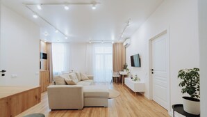 Ein modernes Wohnzimmer mit einer Couch, einem Essbereich und einem an der Wand montierten Fernseher.