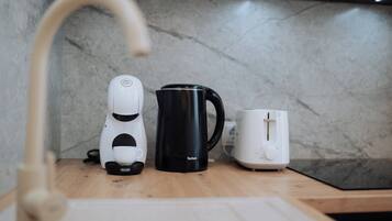 Una cocina con cafetera, una taza negra y un tostador sobre la encimera.