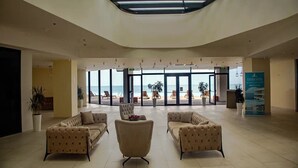 Un amplio vestíbulo con techos altos, grandes ventanales con vista a la playa y varias zonas de estar.