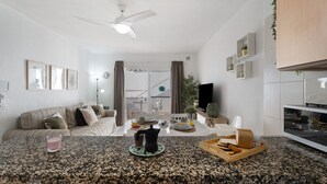 A modern kitchen with granite countertops, a coffee maker, and a dining area with a sofa and a TV. - Vacation 'Serene Terrace and Pool' with Shared Pool, Private Terrace and Wi-Fi (Playa de la Américas)