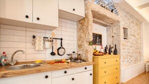 A kitchen with white cabinets, a wooden countertop, and a yellow drawer unit. - Apartment Irma: Studio apartman (Pula)