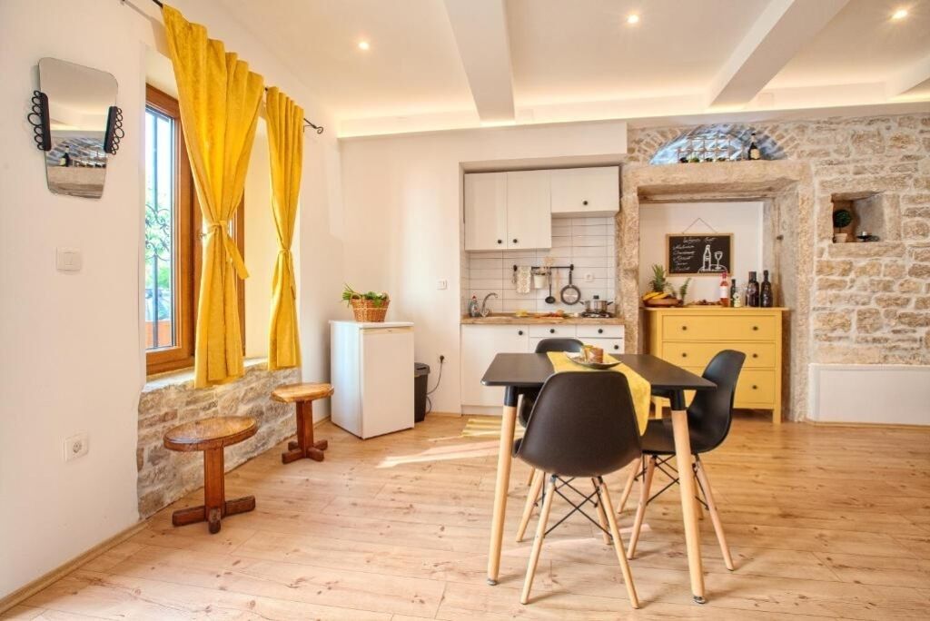 A compact kitchen with white cabinets, a small refrigerator, and a dining area with a table and chairs.