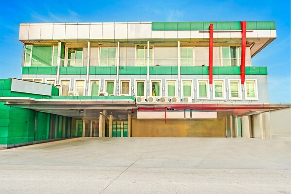 A multi-story building with a flat roof, large windows, and a covered entrance area.