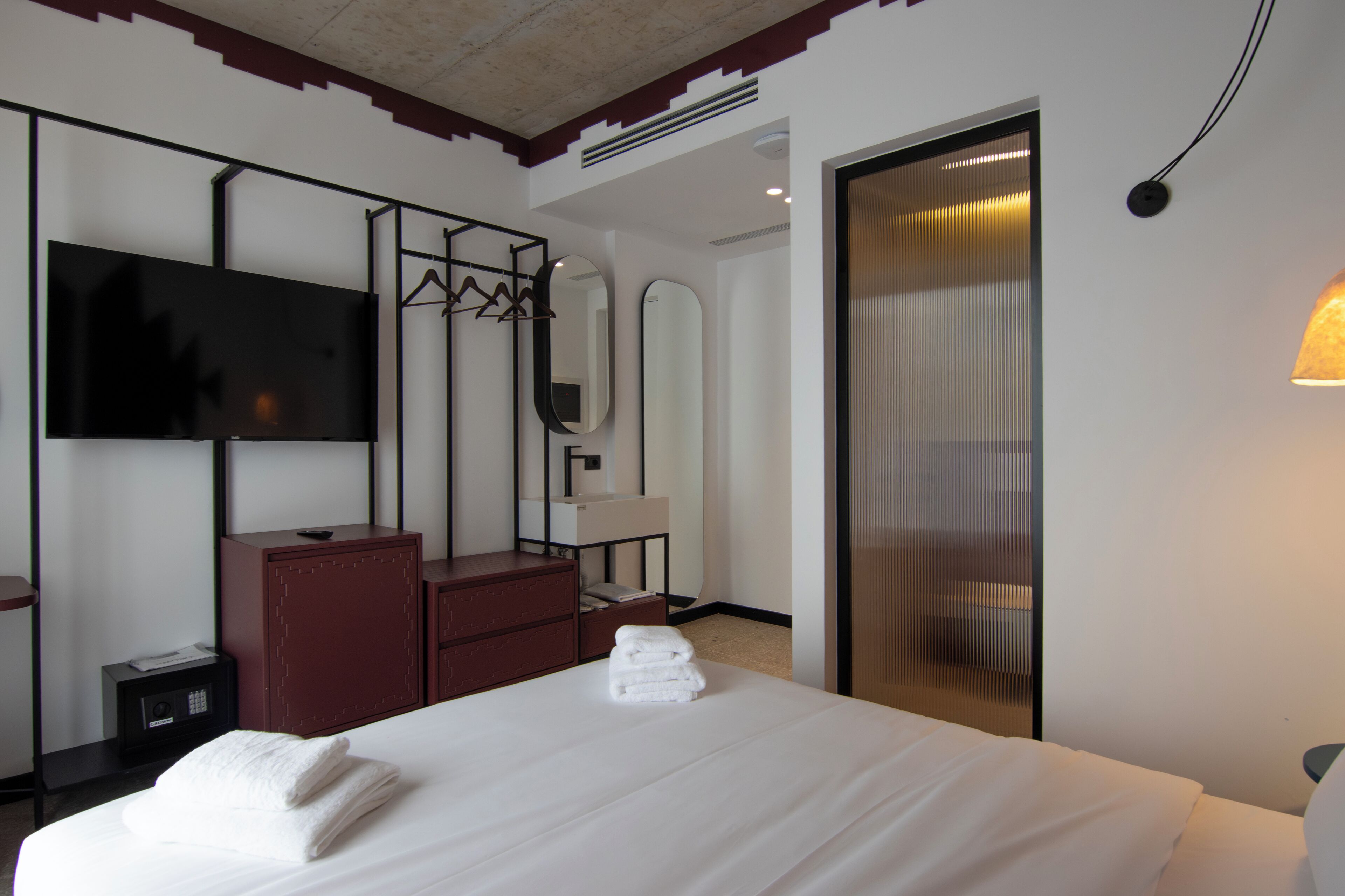 Een hotelkamer met een bed, een televisie, een kledingkast, een spiegel en een schuifdeur.