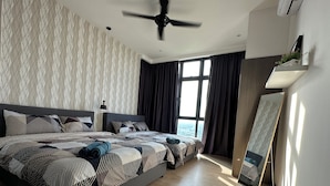 Ein modernes Schlafzimmer mit einem großen Bett, einem Deckenventilator und Blick auf die Stadt durch große Fenster.