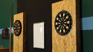 Two dartboards mounted on a wall with a whiteboard between them.