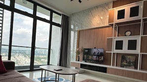 Ein modernes Wohnzimmer mit großem Fenster, Flachbildfernseher, Couchtisch und Sofa.