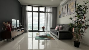 Ein modernes Wohnzimmer mit großem Fenster, einer Couch, einem Couchtisch und einem Fernseher auf einem Standfuß.