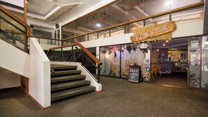 A hotel lobby with a staircase, a sign for 'King's Pub', and a sign offering beer and cocktails. - Canoe Palms Waikiki Pool, Hot Tub, Gym, WiFi, AC (Honolulu)
