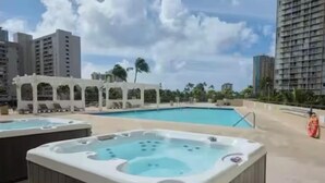 A rooftop pool area with hot tubs, a lounge area, and high-rise buildings in the background. - Canoe Palms Waikiki Pool, Hot Tub, Gym, WiFi, AC (Honolulu)
