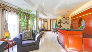 A hotel lobby with a reception desk, seating area, and decorative plants. - Stylish Superior Suite Stay – Townhouse VIP Suite (Makati City)