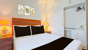 A hotel room with a bed, two bedside lamps, a nightstand, a dresser, a desk with a chair, and a wardrobe. - Stylish Superior Suite Stay – Townhouse VIP Suite (Makati City)