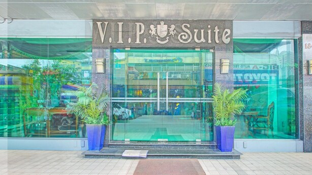 Het uiterlijk van hotel V.I.P. Suite met een glazen gevel, twee potplanten en een rode loper.