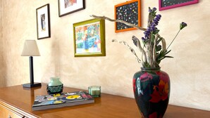 Uma mesa de madeira com um vaso de flores, uma lâmpada, uma vela e um quadro emoldurado.