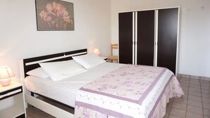 Un dormitorio con cama, mesita de noche, lámpara, armario y un cuadro en la pared.