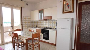 Una cocina con mesa, sillas, un refrigerador y una ventana.