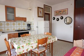 Eine kleine Küche mit Esstisch, Stühlen, Kühlschrank und Herd.