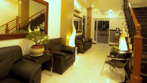 A spacious living area with a staircase, a sofa, a coffee table, and a potted plant.