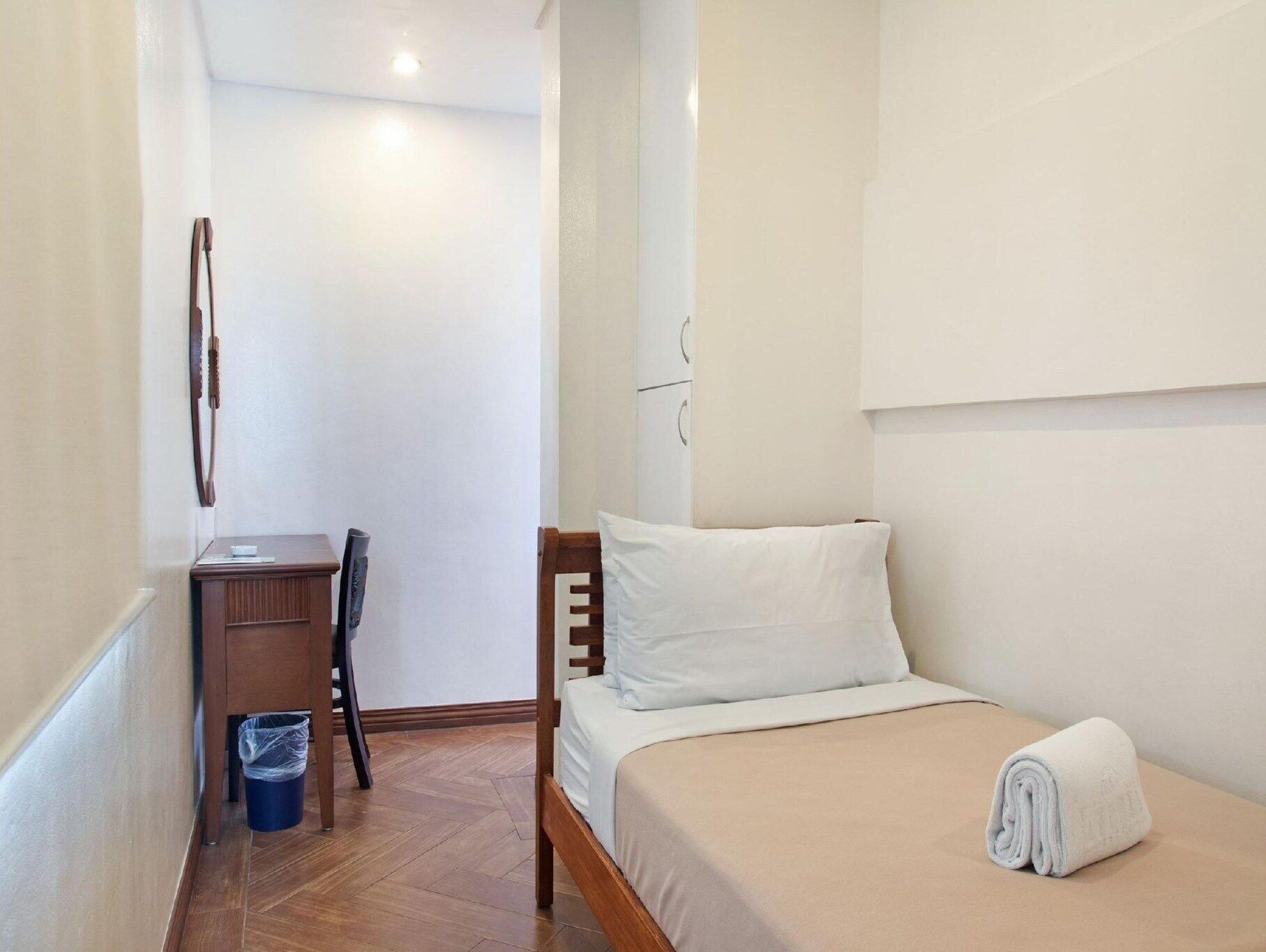 A small, clean room with a single bed, a desk, and a chair.