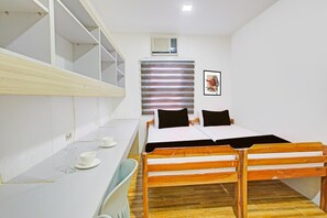 A room with a bed, a desk, and a window with blinds.