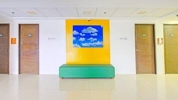 En lobby med en grøn bænk, en gul væg med et sky-maleri, og døre nummereret 405, 407 og 409.