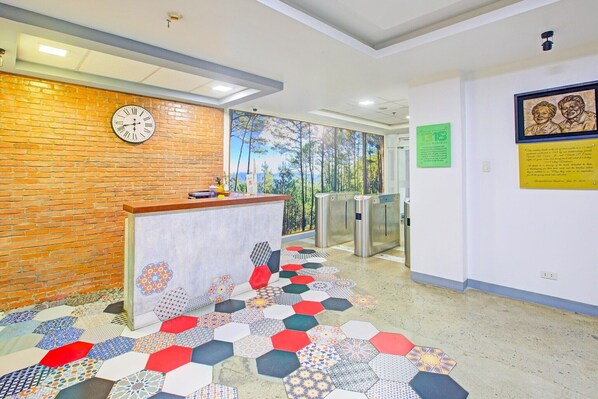 A reception area with a brick wall, a clock, a patterned floor, and a mural.