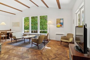 Un salon moderne avec un plancher en bois, un canapé, une table basse et un meuble pour la télévision.