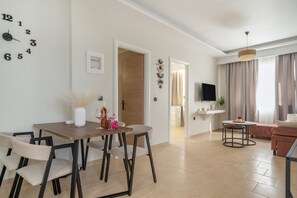 A modern living room with a dining area, a TV, and a sofa.
