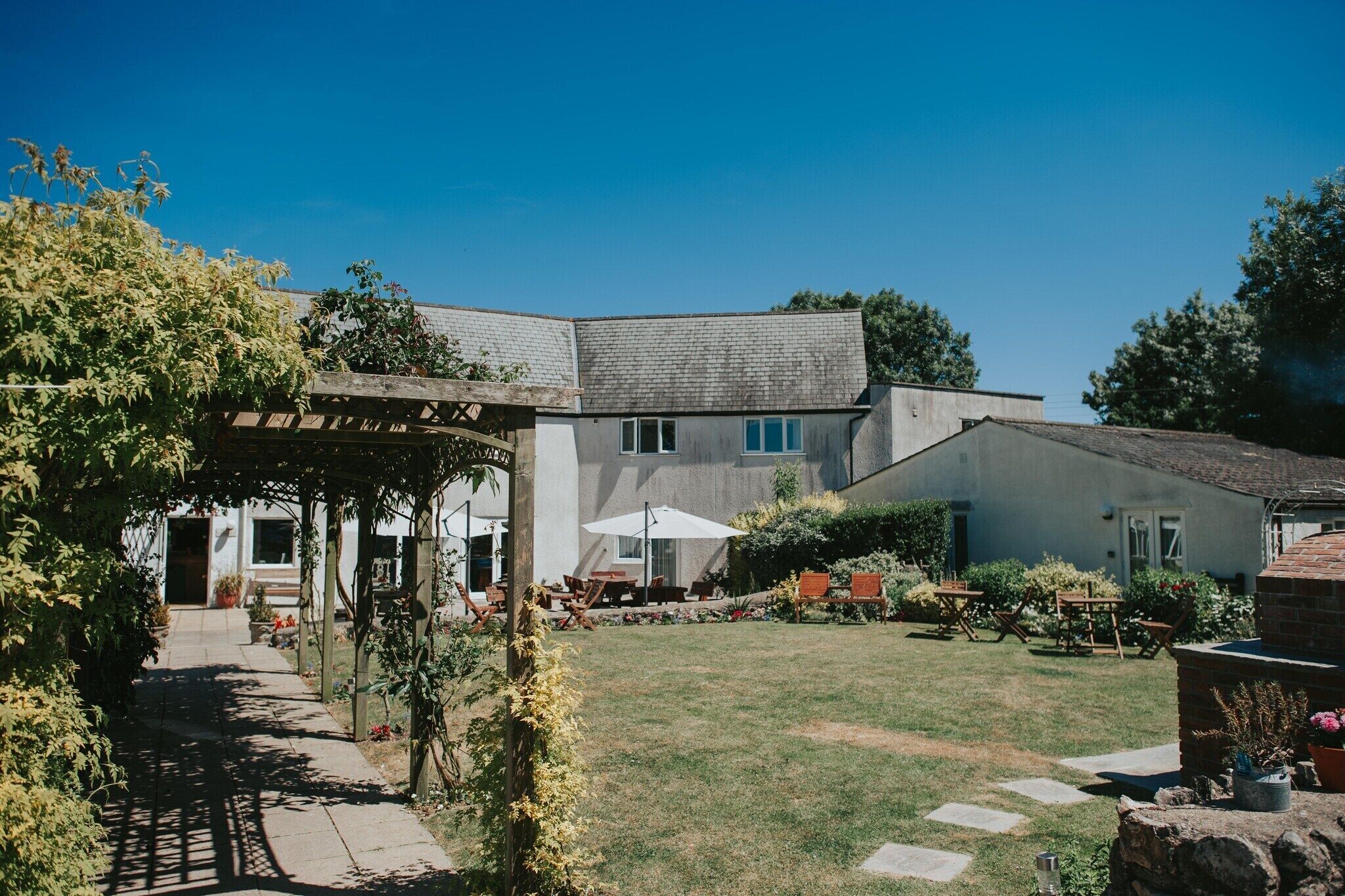 Ein Gebäude mit überdachter Terrasse, Sitzgelegenheiten im Freien und einem gepflegten Rasen.