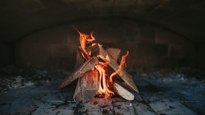 Una chimenea con leña ardiendo y un arco de piedra encima.